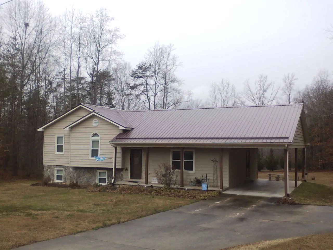 Burgundy metal roof on a tan split level home with an attached carport in Merrimac