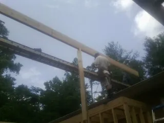 Carpenter setting a ridge beam over a new addition frame — Ice Dam Removal by Roofing Brothers in Merrimac