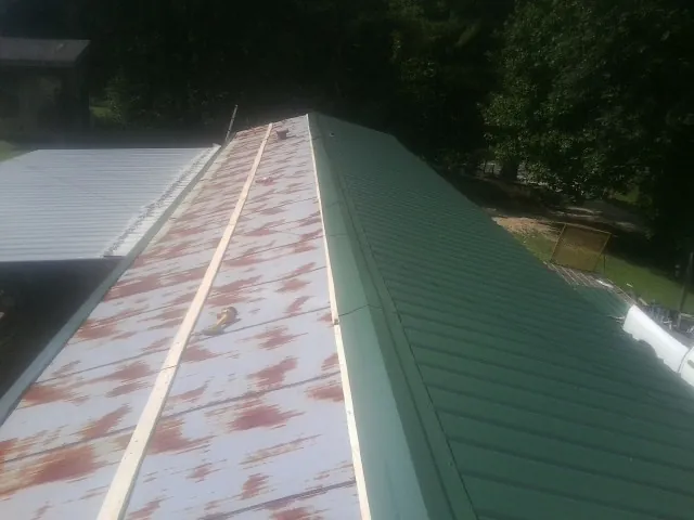 Old rusted panels beside newly installed green metal roofing — Wind Damage Roof Repair by Roofing Brothers in Merrimac